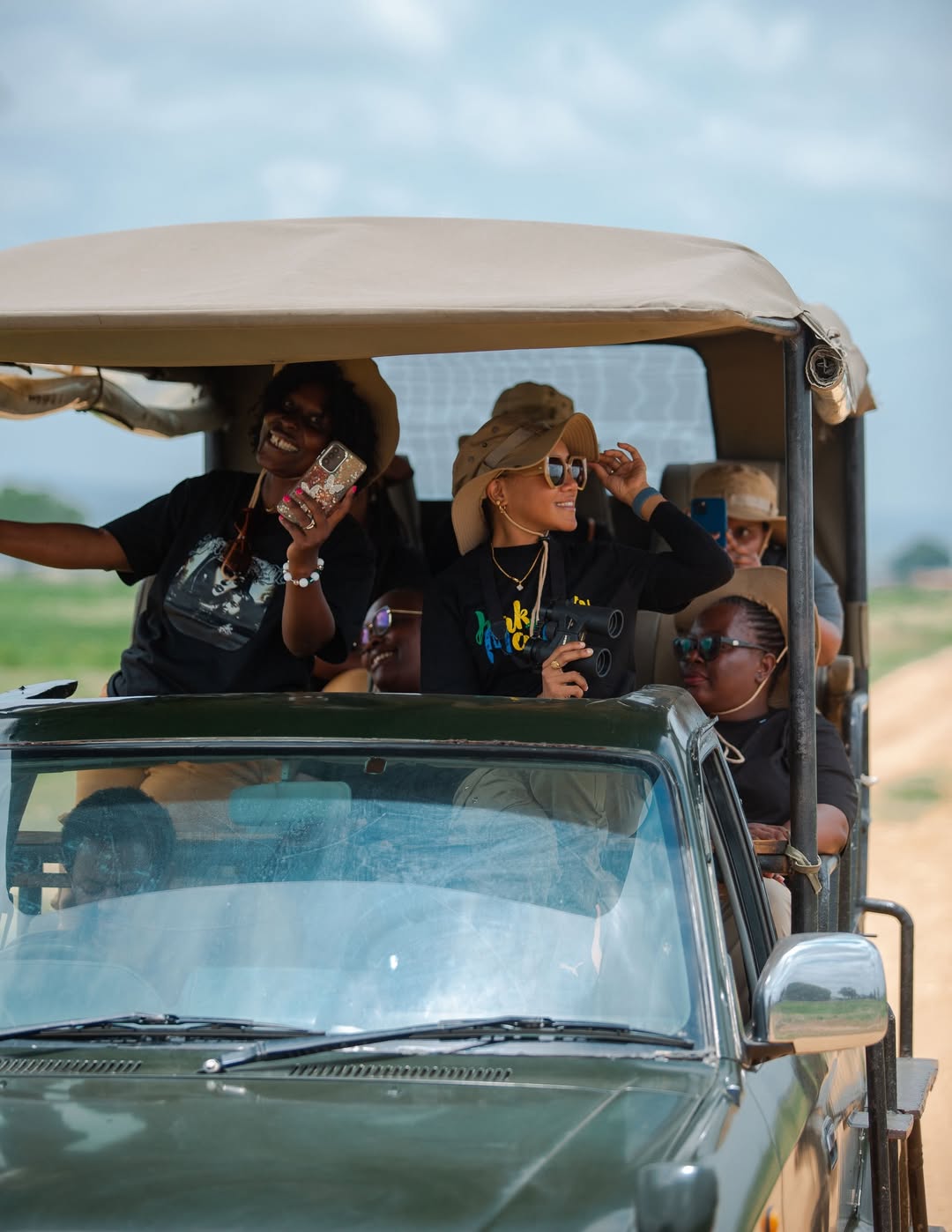 Group of diverse travelers in safari vehicle pointing at wildlife